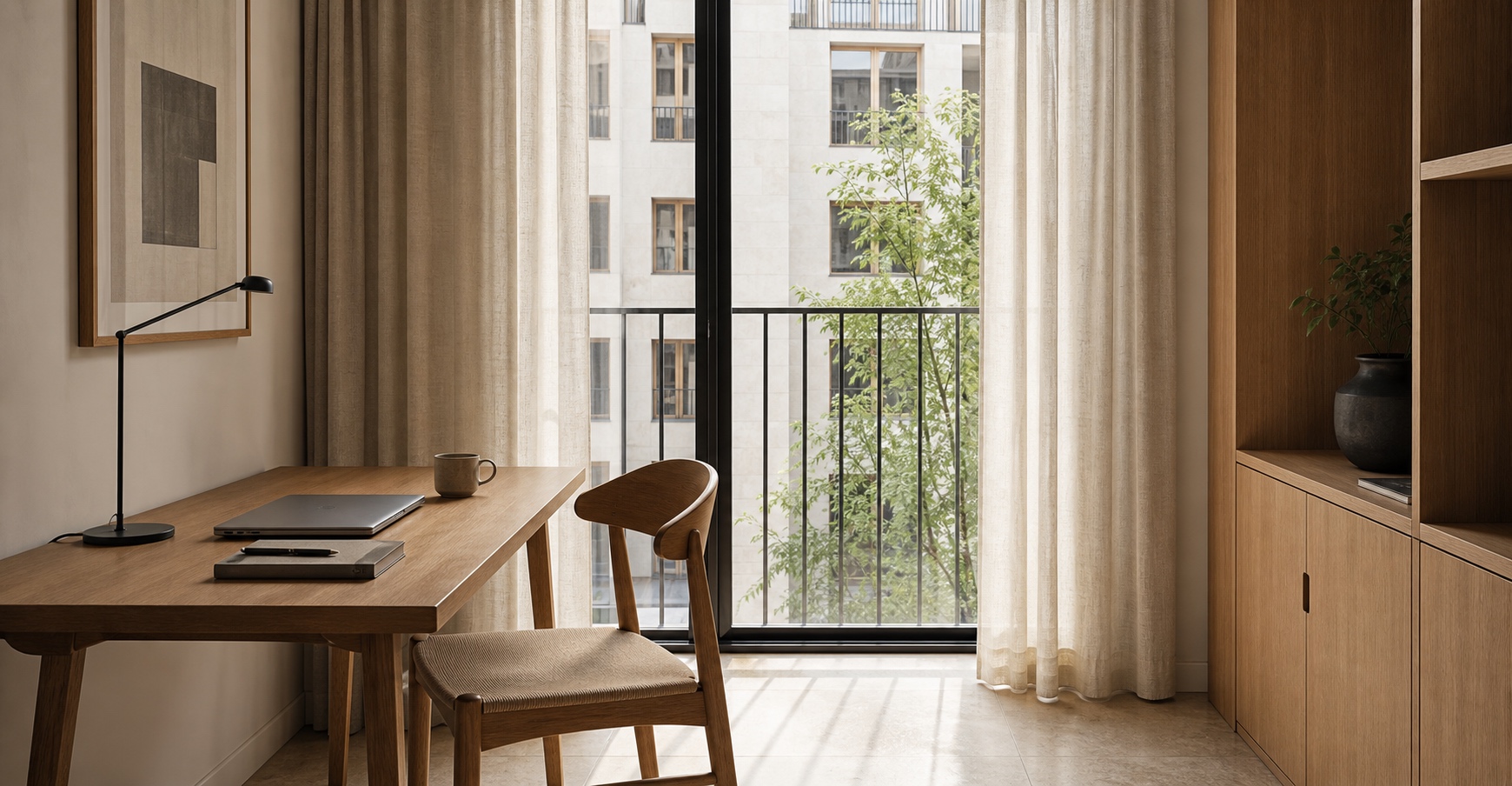 Oak desk by a tall window overlooking the courtyard, set up for a workstay