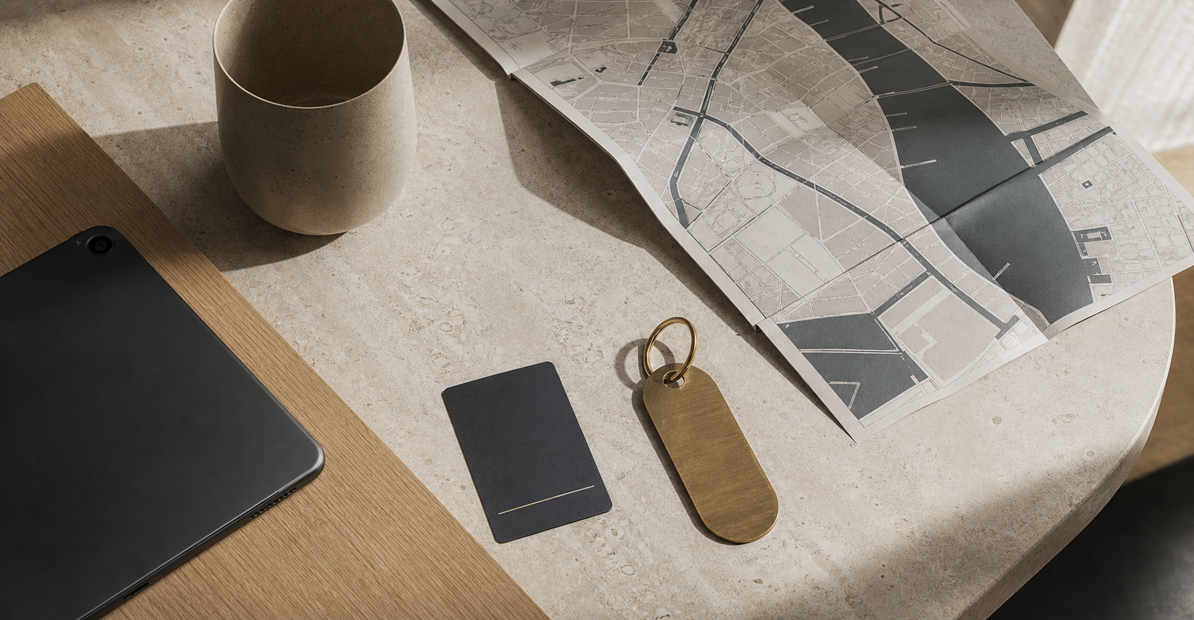 A keycard, brass room tag, and a folded city map on pale limestone