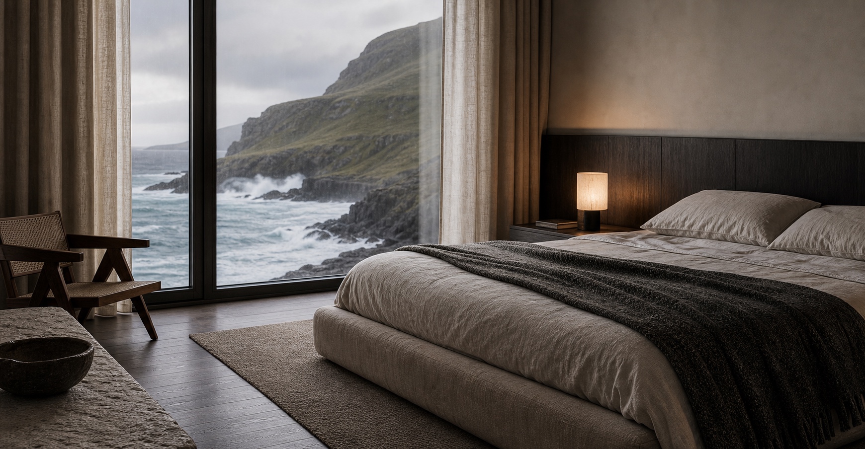 Sea-facing bedroom with linen and a dark timber headboard above the waves
